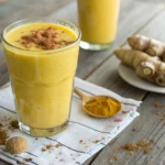 A vibrant and creamy turmeric golden milk smoothie garnished with cinnamon and ginger slices, captured with soft natural lighting.